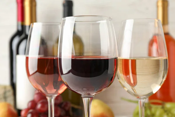 Uva, garrafas e copos com vinho sobre fundo branco, fechar — Fotografia de Stock