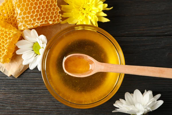 Cuenco con miel, panales y flores sobre fondo de madera, a — Foto de Stock