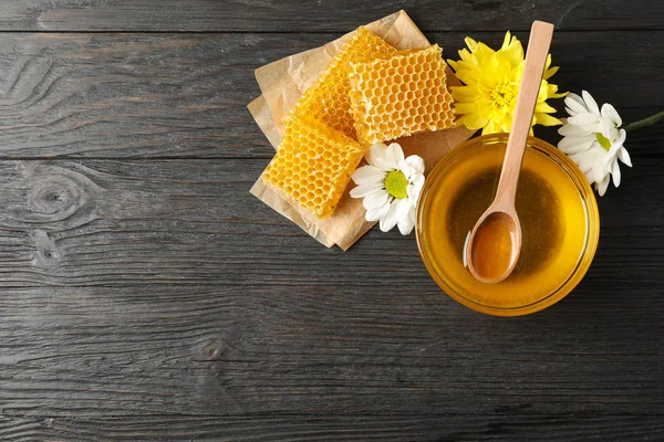 Schaal met honing, honingraten en bloemen op houten ondergrond, co — Stockfoto