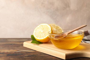 Limon ve kase bal ve ahşap arka plan, boşluk üzerinde dipper ile