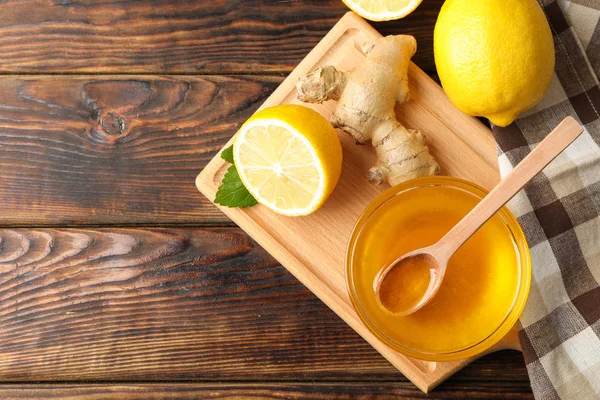 Мед, имбирь, лимоны и полотенце на деревянном фоне, вид сверху — стоковое фото