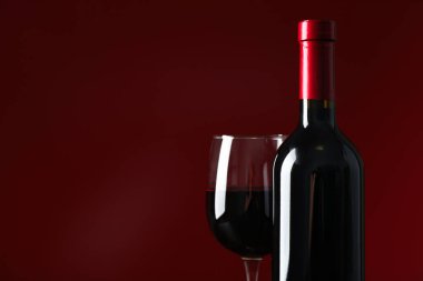 Kırmızı arka plan karşı şarap ile şişe ve cam, kopya alanı