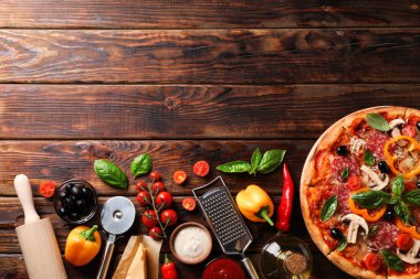 Ahşap arka plan üzerinde lezzetli pizza ve malzemeler, kopya alanı