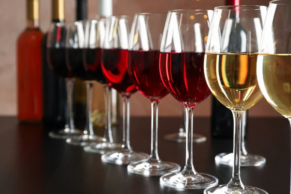 Garrafas e copos com vinho na mesa escura, luzes embaçadas, clo — Fotografia de Stock