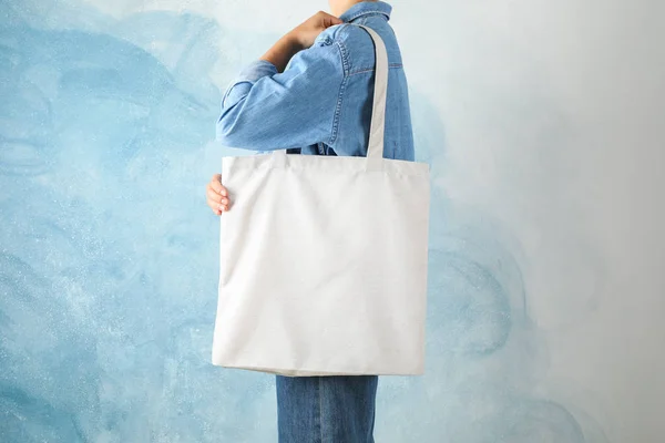 Mavi arka plan, boş boşluk karşı çanta tutan genç kadın