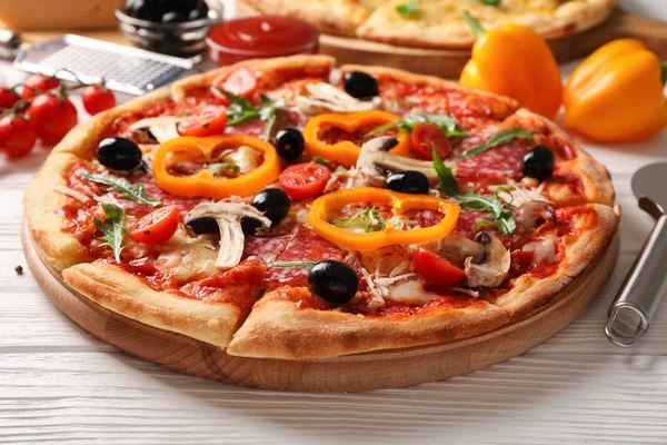 Смачна піца та інгредієнти на білому дерев'яному фоні, закрити — стокове фото