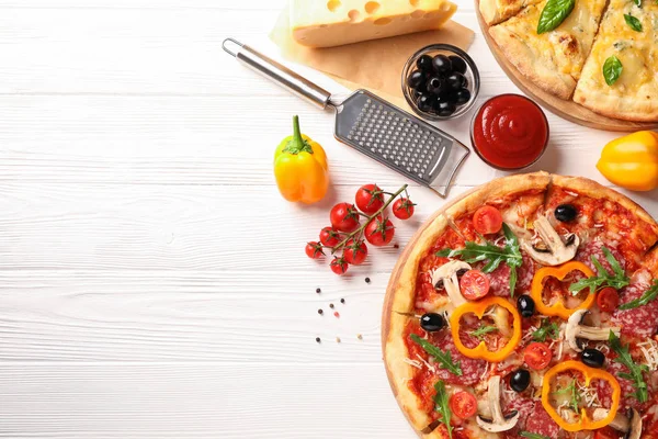 Lezzetli pizza ve beyaz ahşap arka plan üzerinde malzemeler, kopya