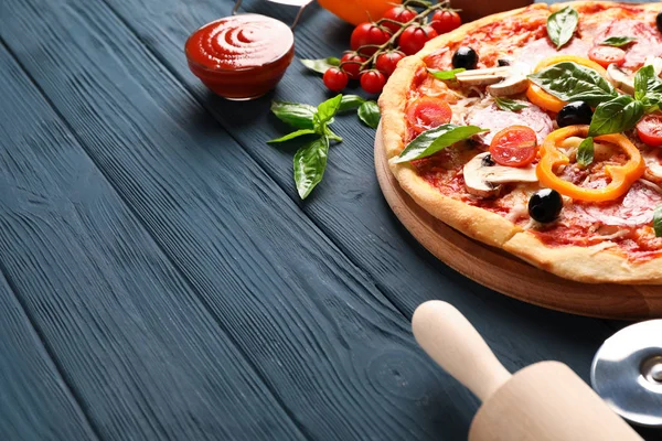 Deliciosa pizza e ingredientes sobre fondo de madera, espacio para copiar — Foto de Stock