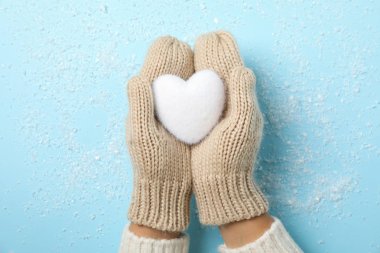 Kız kar ile mavi arka plan üzerinde elleri beyaz kalp tutarak, 