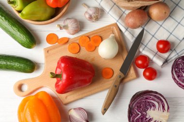 Beyaz ahşap arka plan üzerinde sebze, tahta ve bıçak, üst görünüm