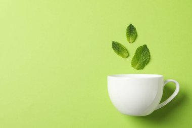 Beyaz fincan ve yeşil arka plan üzerinde yaprakları, metin için alan