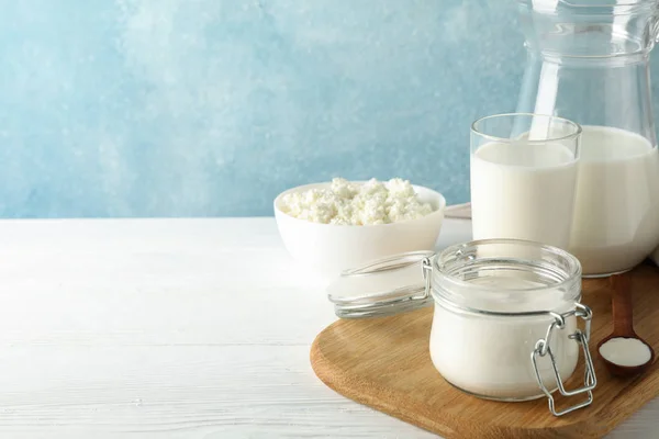 Čerstvé mléčné výrobky na bílém dřevěném stole, kopírovací prostor — Stock fotografie