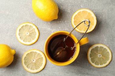 Gri arka planda bir fincan çay ve limon, üst görünüm