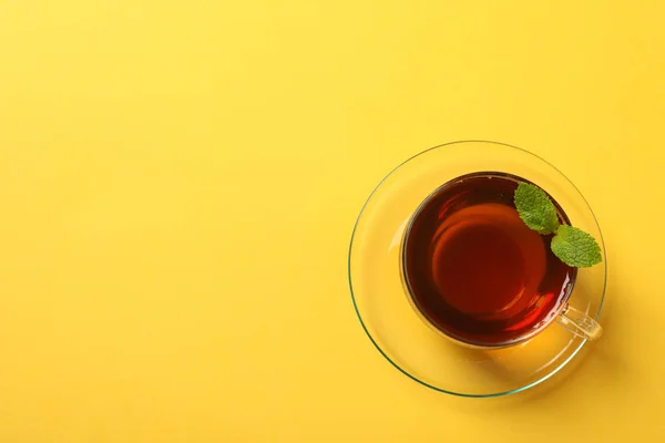 Sarı arka planda bir fincan çay ve nane yaprağı, metin için alan — Stok fotoğraf