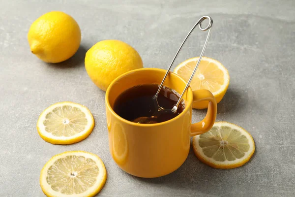 Чашка чая и лимонов на сером фоне, крупный план — стоковое фото