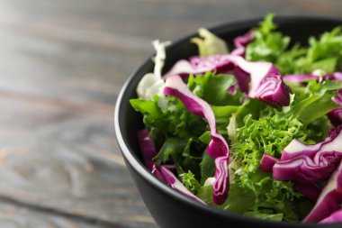 Ahşap arka plan üzerinde taze sebze dilimleri ile Siyah kase, clo