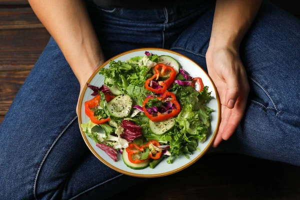 Junge Frau in Jeans mit Salat auf hölzernem Hintergrund — Stockfoto