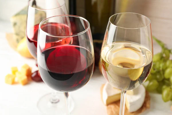Uva, garrafas e copos com vinho sobre fundo branco, fechar — Fotografia de Stock