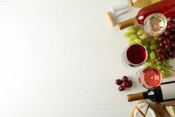 Uva, queijo, garrafas e copos com diferentes vinhos em branco — Fotografia de Stock