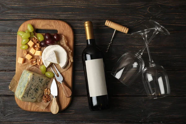 Bottiglia di vino, bicchieri, formaggio e frutta su sfondo di legno , — Foto Stock
