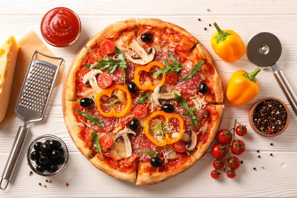 Deliciosa pizza e ingredientes sobre fondo de madera blanca, superior — Foto de Stock