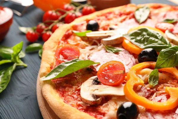 Deliciosa pizza e ingredientes sobre fondo de madera, de cerca — Foto de Stock