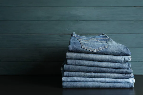 Stack of jeans pants on black table, space for text — Stock Photo, Image
