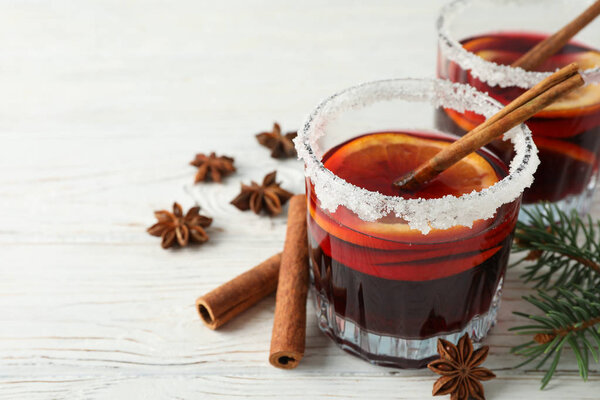 Glasses of tasty mulled wine on white wooden background, space f