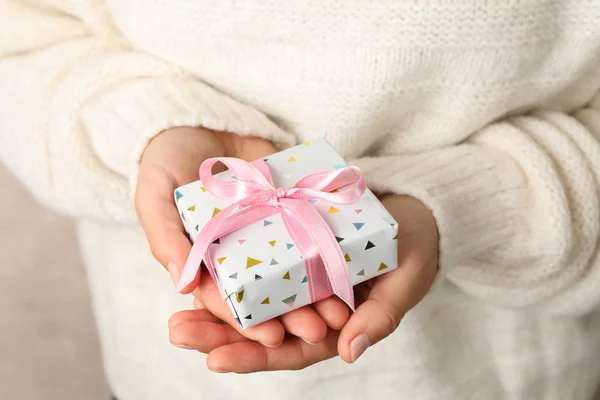 Woman in sweater holding gift box with pink bow, close up — ストック写真