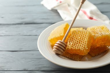 Ahşap zemin üzerinde dipper ve bal peteği tabağı, boşluk