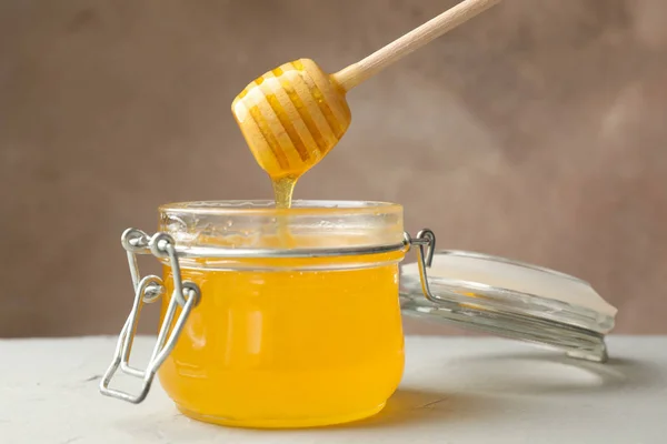 Tarro de vidrio con miel y cazo sobre fondo blanco, de cerca — Foto de Stock