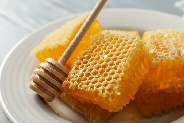 Tallrik med dipper och honeycombs på trä bakgrund, närbild — Stockfoto