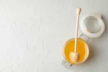 Beyaz zemin üzerinde bal ve kepekli cam kavanoz, üst görünüm