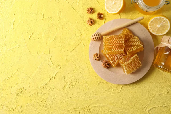 Walnoot, honingraten, potten met honing, dipper en citroen op geel — Stockfoto