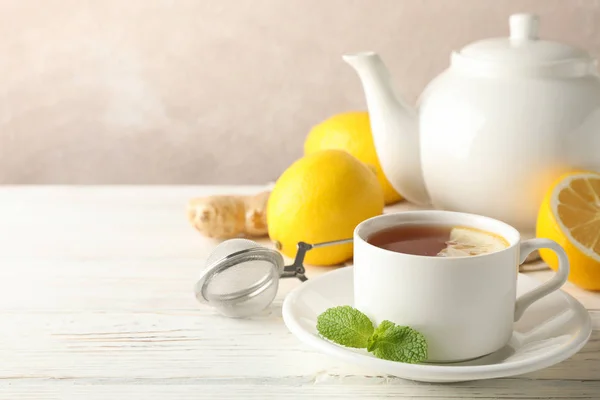 Filiżanka herbaty z cytryną, mięta, sito, imbir i czajnik na drewnie — Zdjęcie stockowe