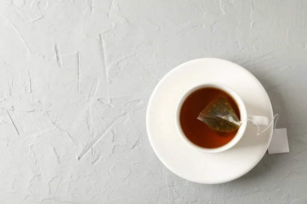 Gri arka planda çay poşeti olan bir fincan çay, üst manzara. — Stok fotoğraf