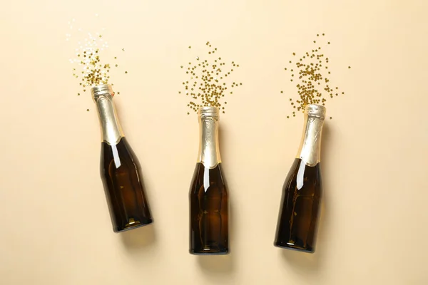 Bouteilles de champagne et paillettes sur fond beige, espace pour tex — Photo