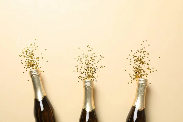 Бутылки шампанского и блеск на бежевом фоне, место для текса — стоковое фото