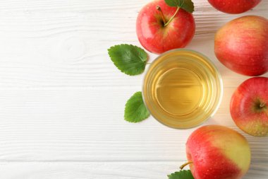 Ahşap arka planda meyve suyu olan elmalar ve cam, üst manzara.