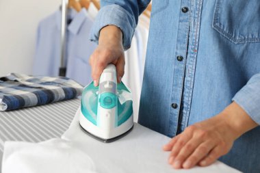 Ütü masasında ütü yapan genç kadın, mesaj için boşluk.