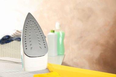 Ütü masasında demir ve sarı tişört, metin için boşluk