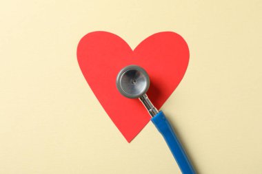 Bej arka planda steteskop ve kalp, yakın çekim. Sağlık Hizmetleri