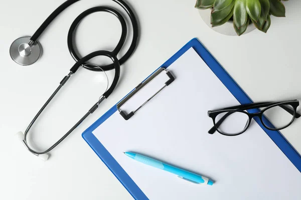 Stethoscope, tablet, glasses, pen and plant on white background, — Stock Photo, Image
