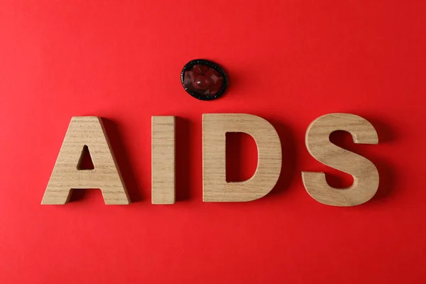 Word Aids i prezerwatywa na czerwonym tle, miejsce na tekst — Zdjęcie stockowe