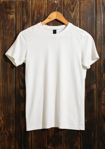 Hanger with blank white t-shirt on wooden background, space for — Stok fotoğraf