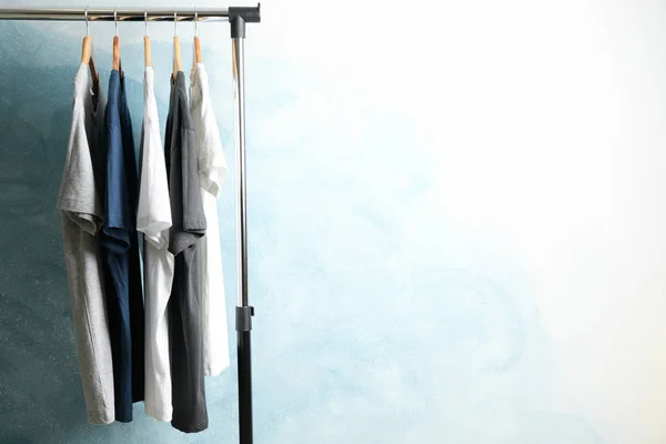 Rack com camisetas em branco no fundo azul, espaço para texto — Fotografia de Stock