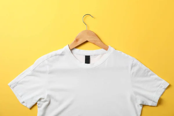 Gancho com t-shirt branca em branco no fundo amarelo, espaço para — Fotografia de Stock