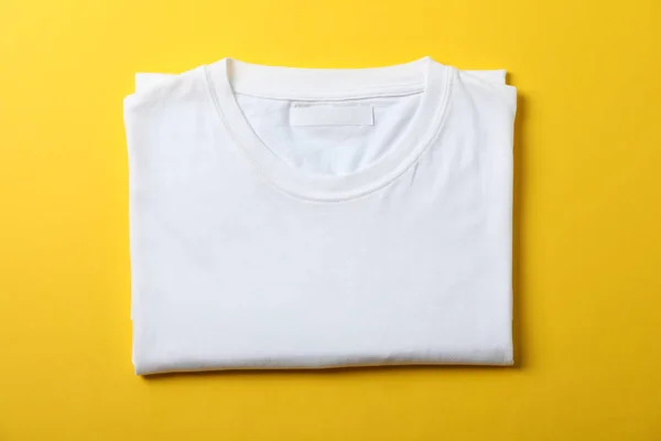 Camiseta blanca plegada en blanco sobre fondo amarillo, espacio para texto —  Fotos de Stock