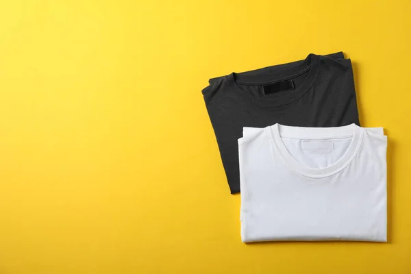 Camisetas em branco dobradas no fundo amarelo, espaço para texto — Fotografia de Stock