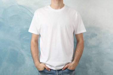 Men in blank white t-shirt against blue background, space for te